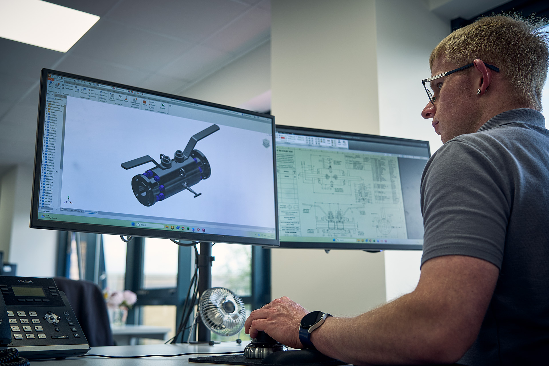 Colson Valves engineer reviewing 3D CAD valve design in SolidWorks alongside engineering drawings at Rotherham office