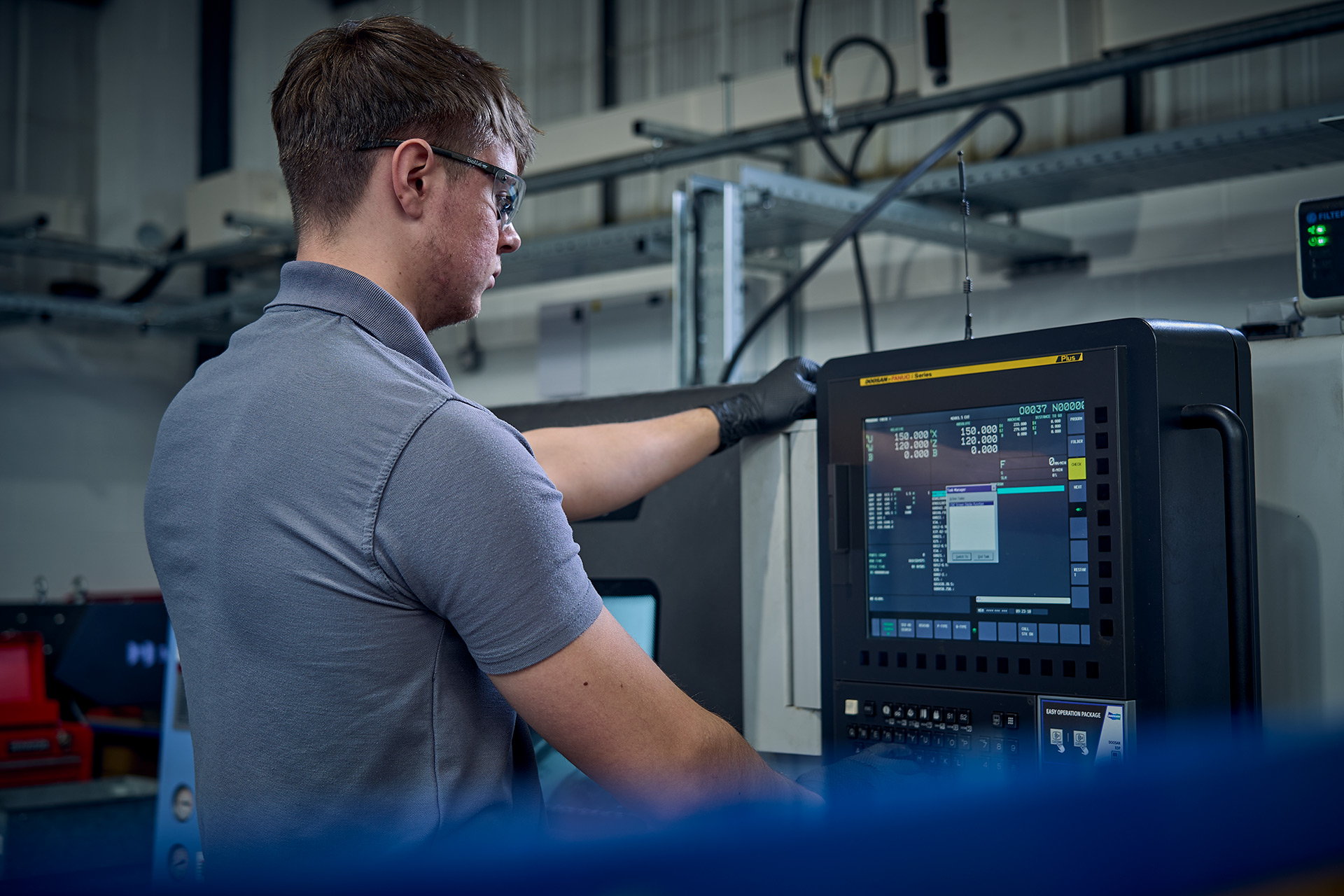 Colson Valves engineer programming Doosan CNC machine control panel during valve component manufacturing